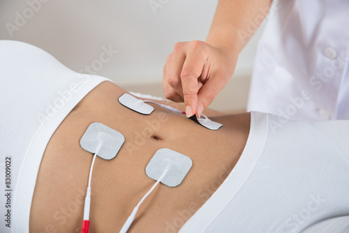 Therapist Placing Electrodes On Woman's Stomach photo