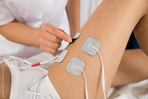 Tableau sur toile Therapist Placing Electrodes On Woman's Thigh