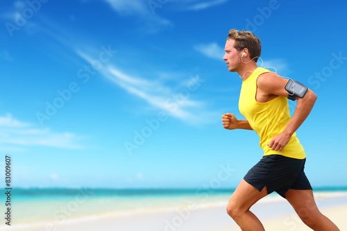 Runner running listening smartphone music on beach