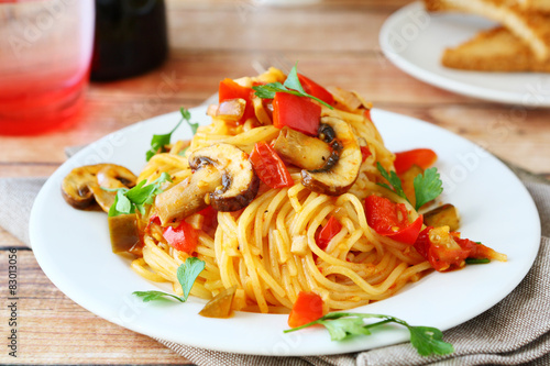 Spaghetti with mushrooms and peppers on a white plate