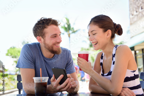 Couple on cafe looking at smart phone app pictures