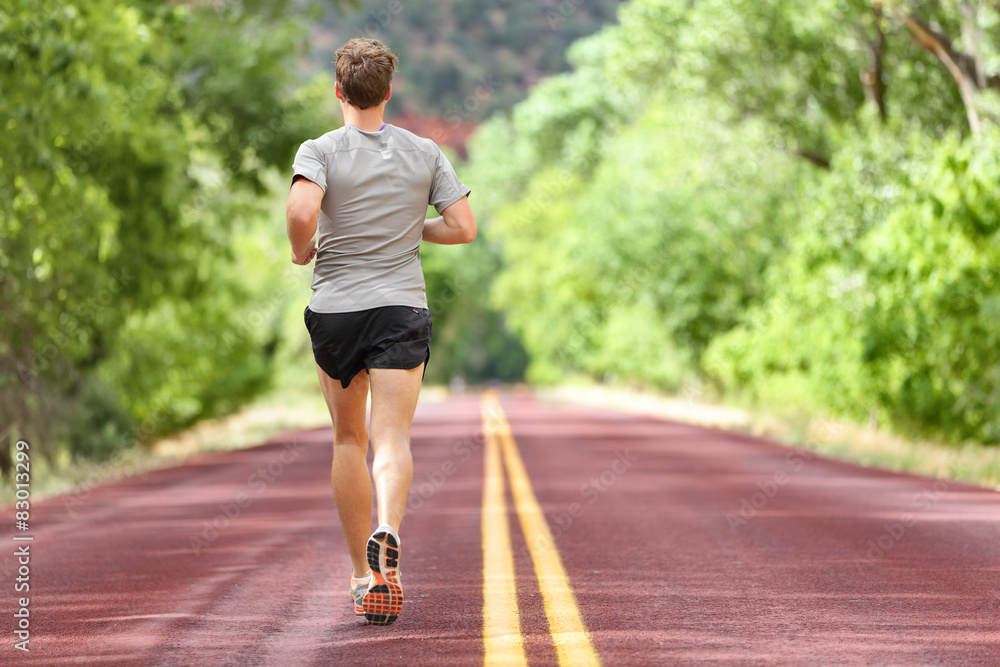 Male runner running on road training for fitness Male runner running on road training for fitness