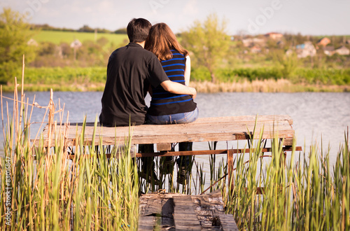 love couple sitting on the bridge on the river bank photo