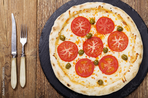 Pizza vegetarian on plate on stone black try with fresh tomatoes