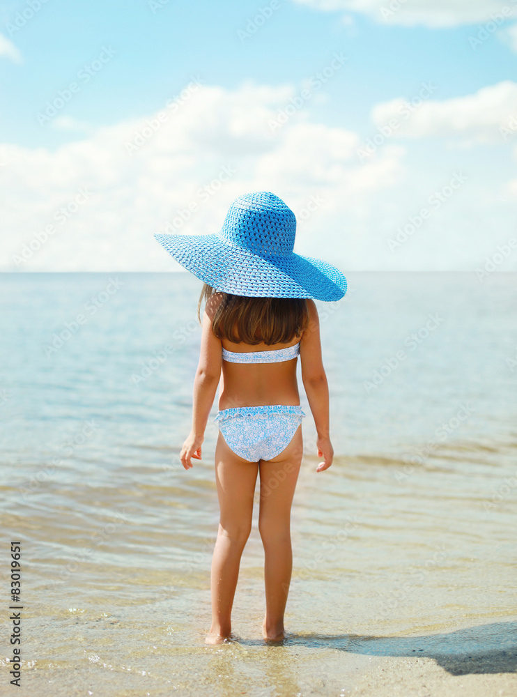 Summer travel photo pretty little girl in straw hat on the beach