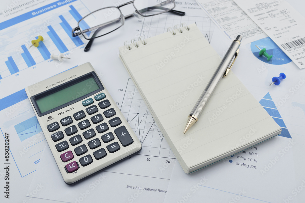 Pen, calculator and notebook on financial chart and graph, accou Pen, calculator and notebook on financial chart and graph, accou