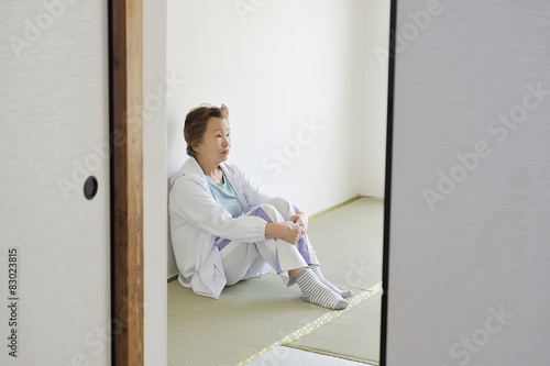 部屋の片隅で寂しく座っているシニアの日本人女性