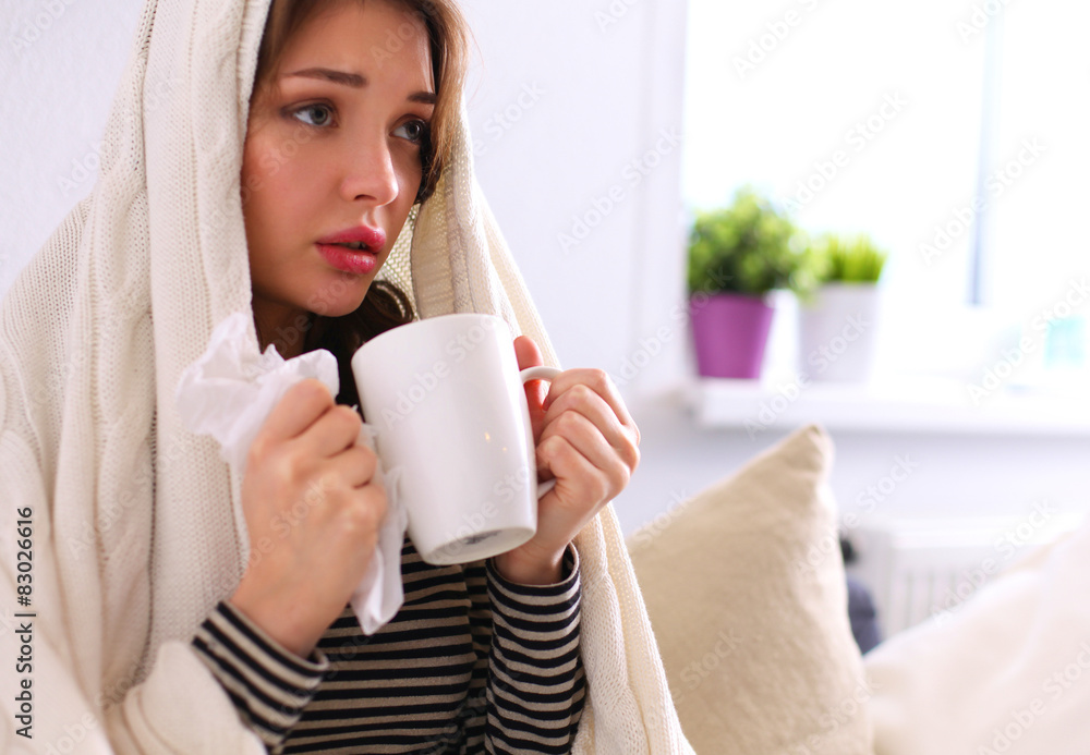 Sick woman covered with blanket holding cup of tea sitting on Sick woman covered with blanket holding cup of tea sitting on
