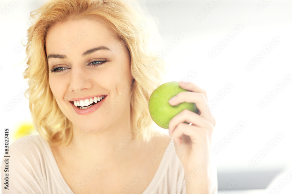 Young woman eating a green apple at home Young woman eating a green apple at home