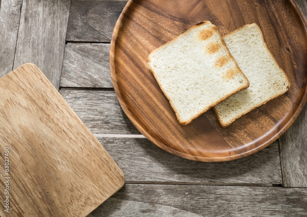 Toast bread on wooden plate and wooden breadboard