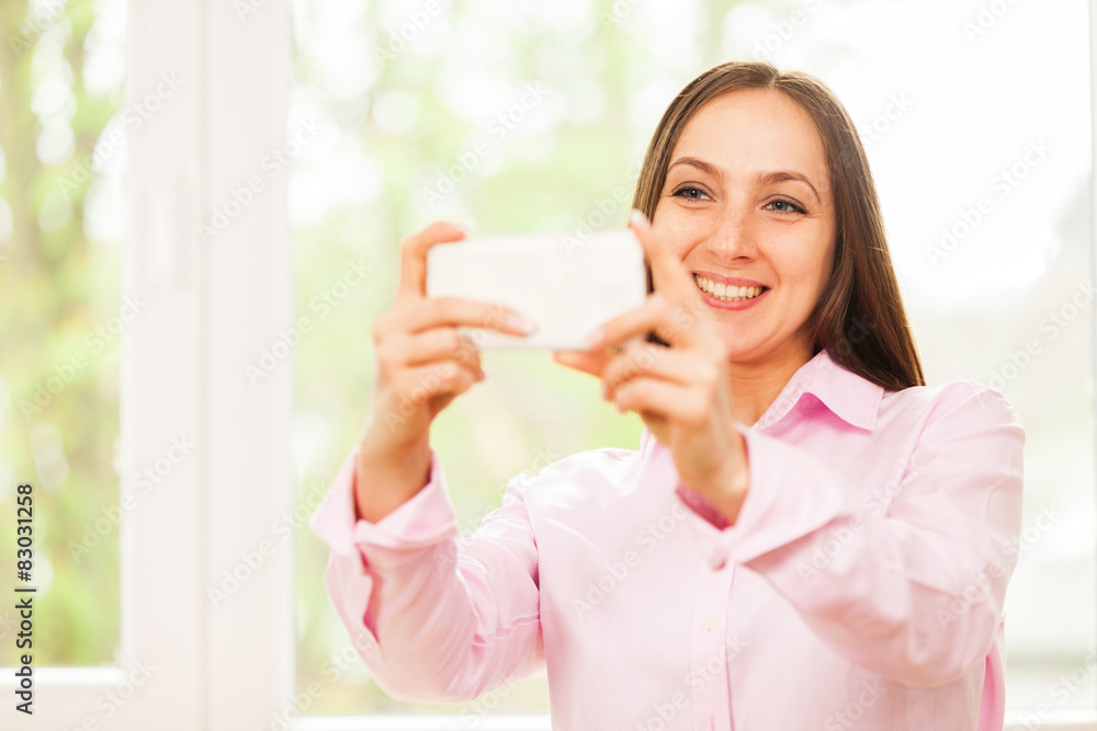 Smiling caucasian woman with pink shirt is doing a selfie with h Smiling caucasian woman with pink shirt is doing a selfie with h
