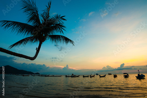Sunset and sea with boat and coconut tree