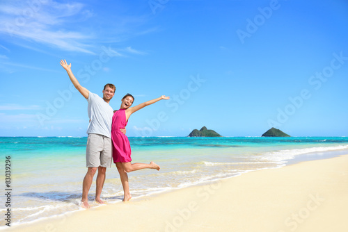 Beach vacation happy carefree couple arms raised