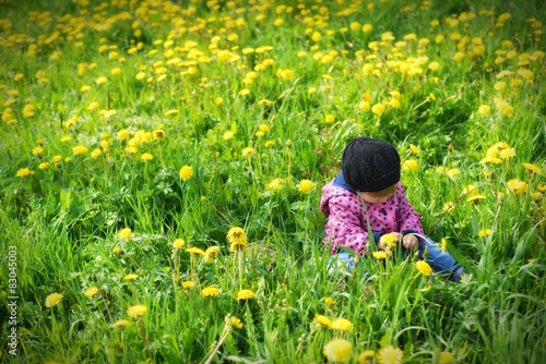 Young girl on green meadow full of yellow flowers.