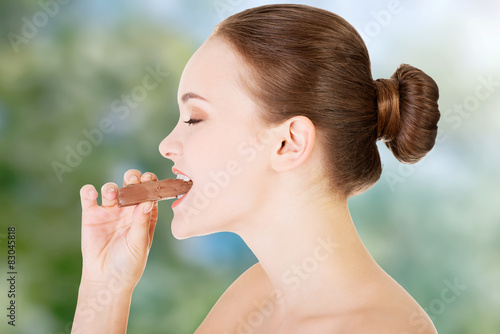 Young woman eating chocolate bar.