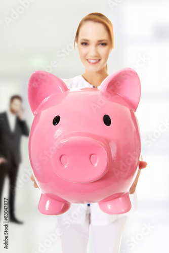 Young female doctor holding a piggybank. photo