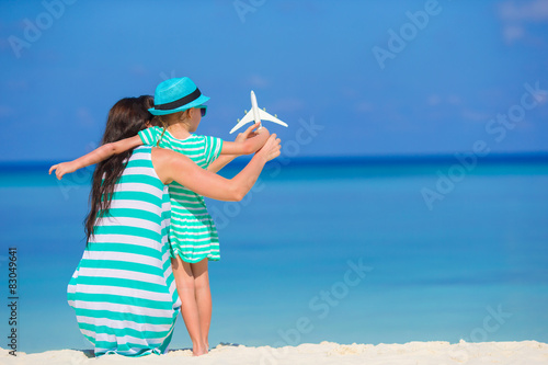 Young woman and little girl with miniature of airplane at beach