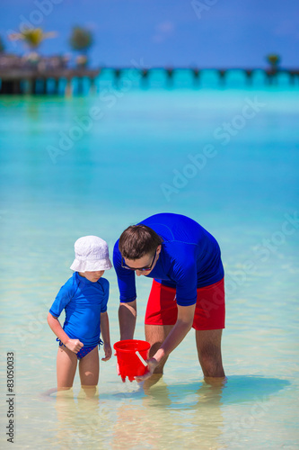 Happy father and little daughter have fun on tropical beach