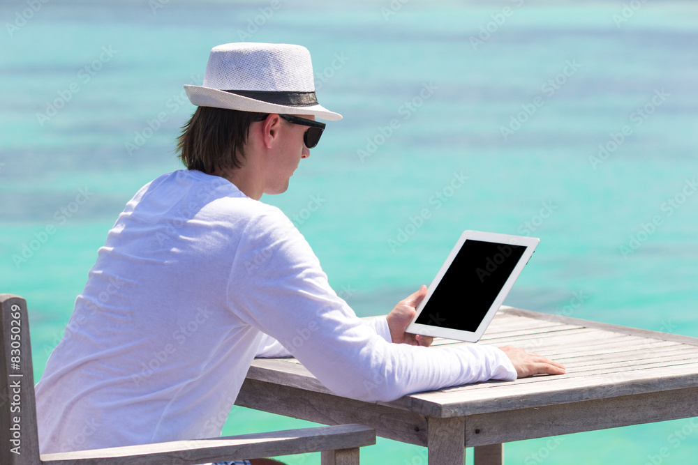 Young man with laptop at tropical beach