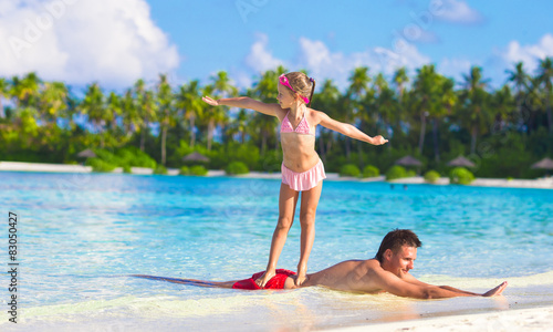 Photography Father with little daughter at beach practicing surfing position