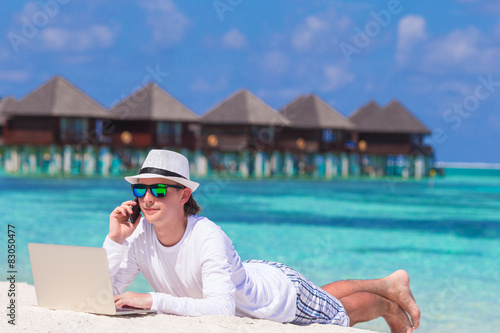Young man with tablet computer and cell phone on tropical beach