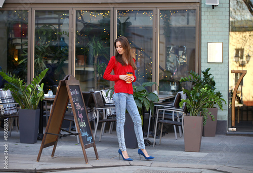 Young beautiful girl in jeans and a red blouse is walking down t