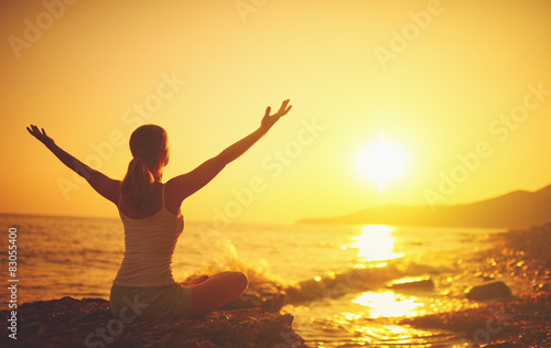 Fotografering yoga at sunset on  beach. woman doing yoga