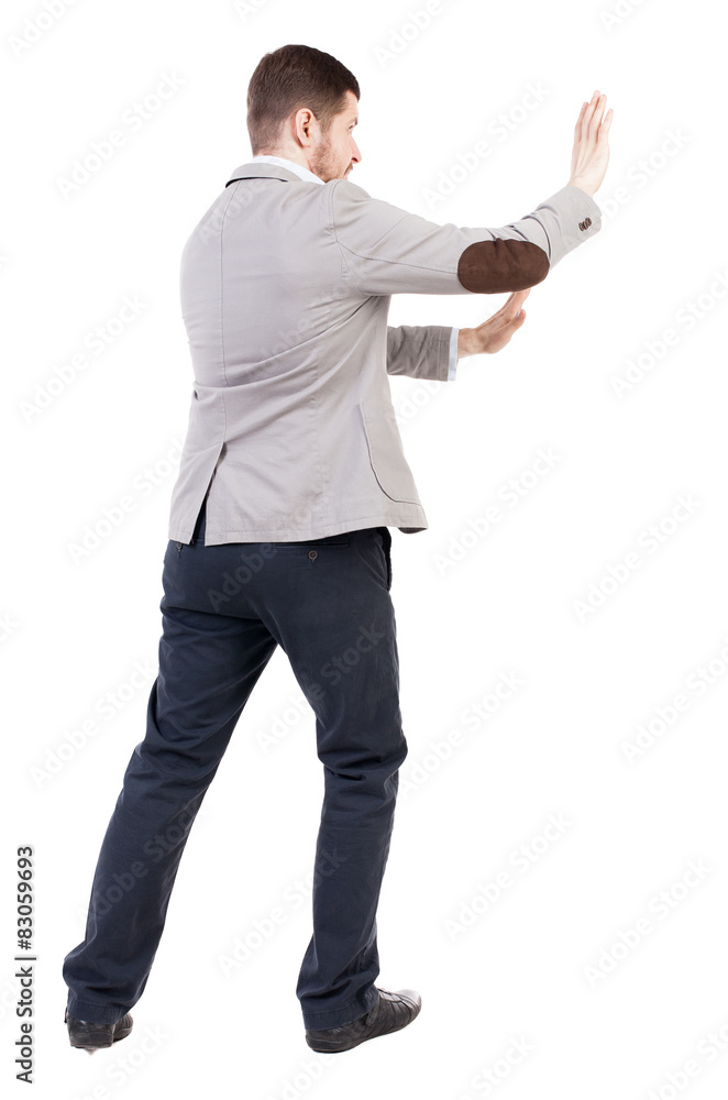 back view of business man pushes wall. back view of business man pushes wall.