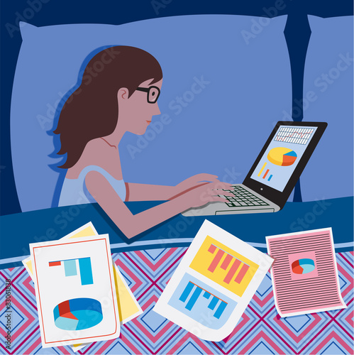 Woman in bed at night working on the laptop
