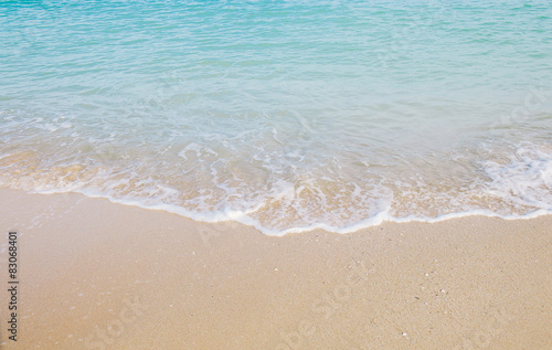 Soft blue wave roll into sandy beach, texture background