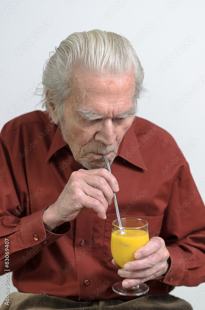 Rentner trinkt mit einem Strohhalm Orangensaft Rentner trinkt mit einem Strohhalm Orangensaft