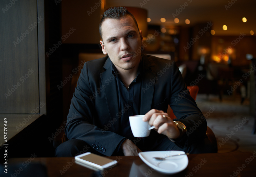 cheerful businessman drinking coffee in restaurant