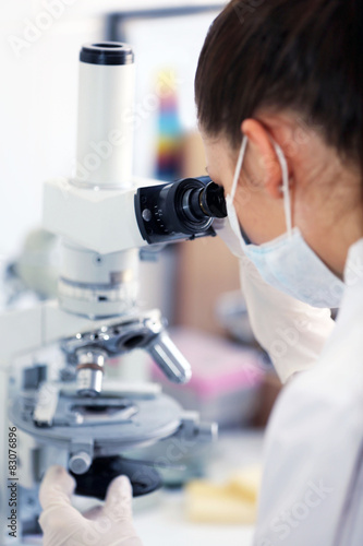 Female scientist looking through a microscope in laboratory