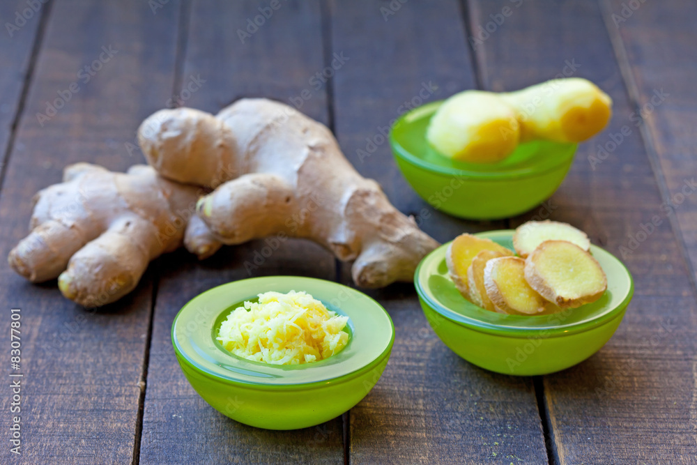 Fresh ginger root, sliced and grated ginger in green bowls