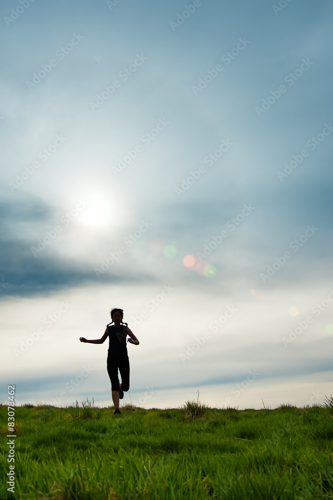 Silhouette of a girl with braids running in a meadow Silhouette of a girl with braids running in a meadow
