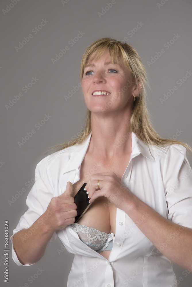 Woman putting mobile phone into her bra for safe keeping Stock Photo