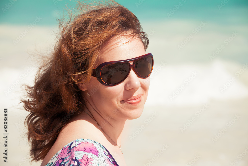 Young smiling woman in sunglasses on a beach Young smiling woman in sunglasses on a beach