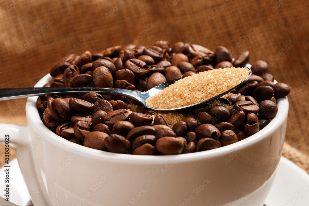 Cup filled with coffee beans and spoon with brown sugar Cup filled with coffee beans and spoon with brown sugar