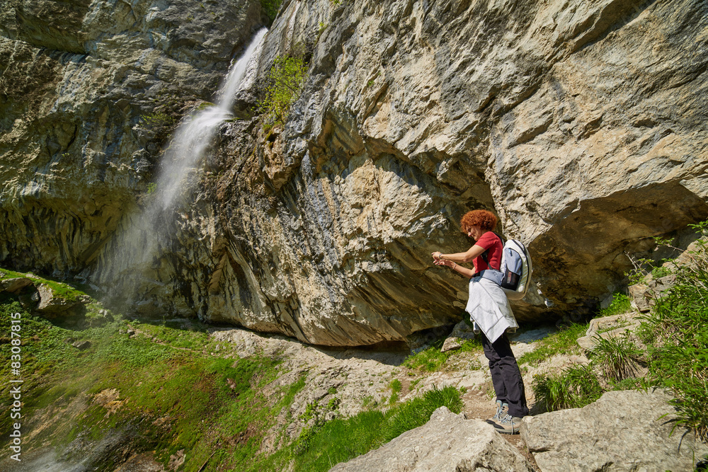 Woman taking photos near the waterfall