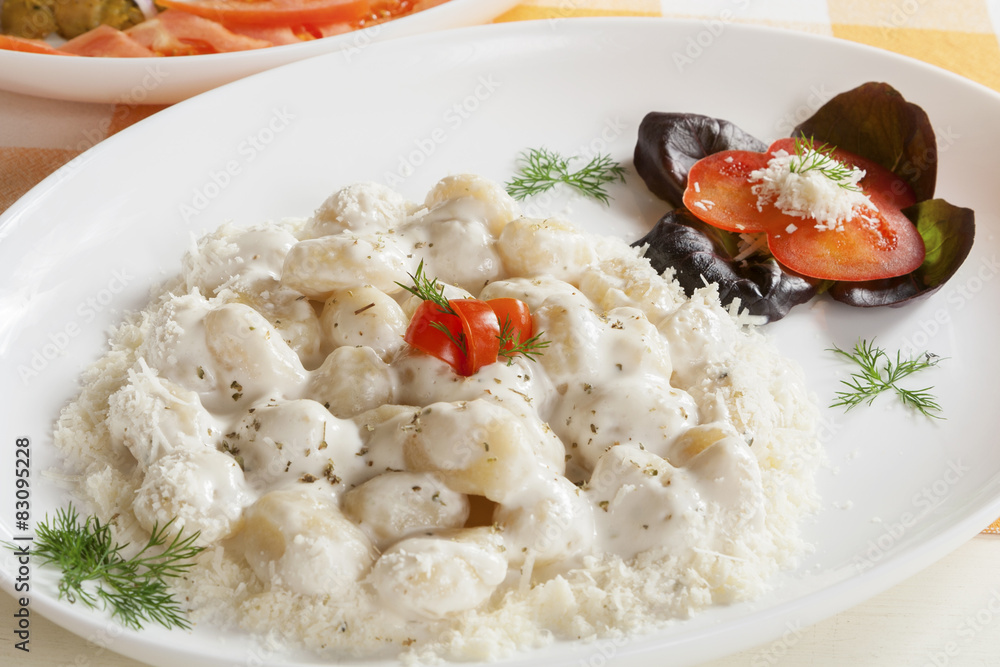 Servings of gnocchi with white truffle sauce with garnish.