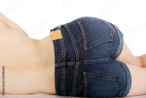 Shirtless woman lying in jeans shorts.