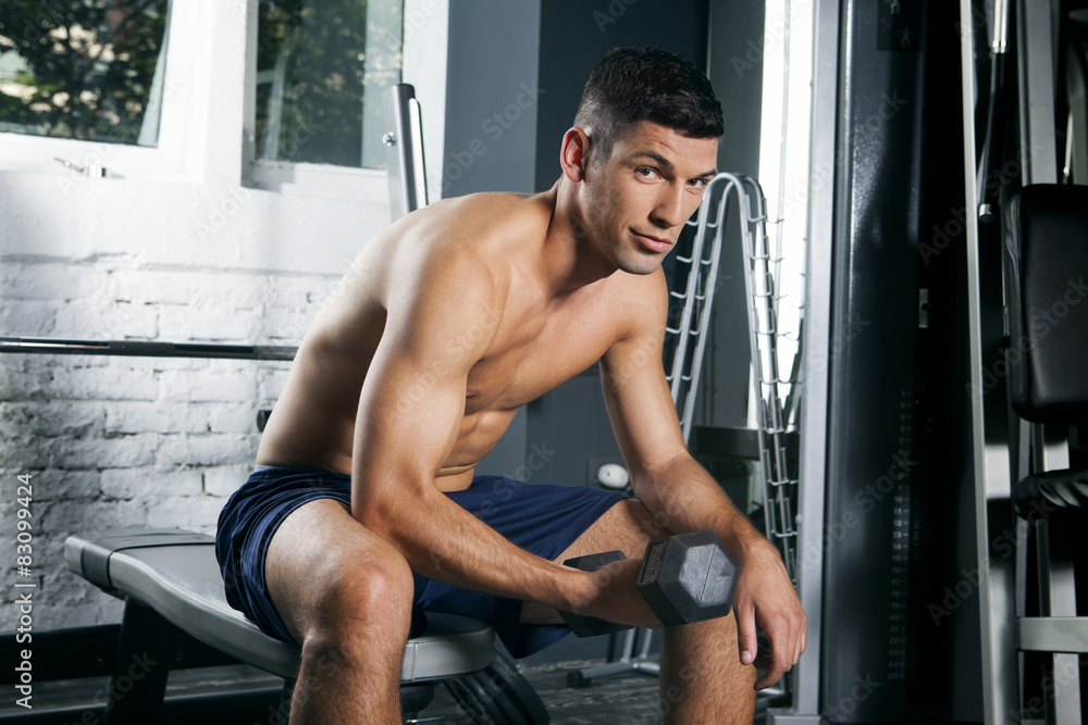 Obraz premium Muscular man in gym training with dumbbell