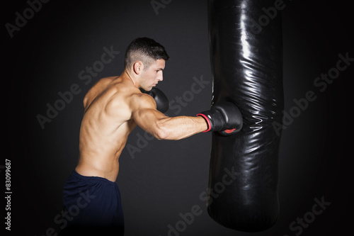 Muscular man training with punching bag at gym