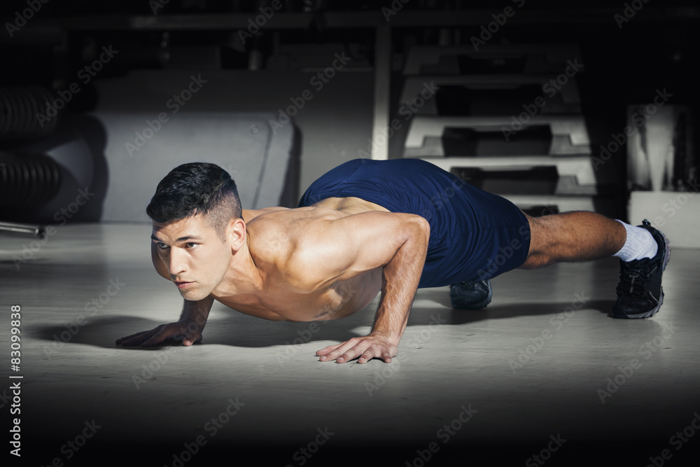 Fototapeta premium Muscular man doing push ups at gym