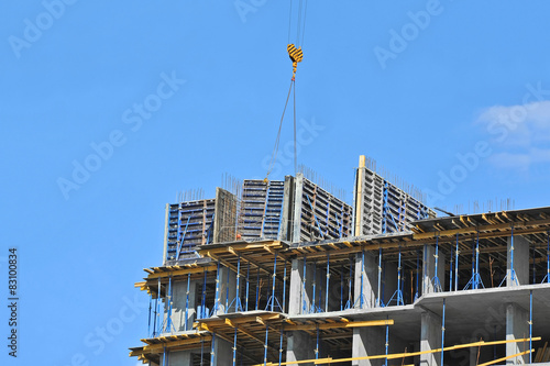 Crane hoisting formwork over construction site work