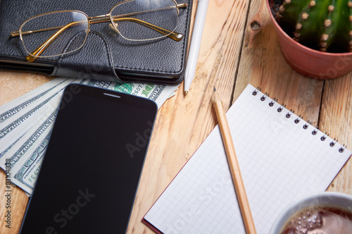 Workplace with notebook, phone, laptop, tea, money, glasses. photo