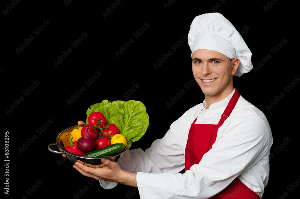 Young chef holding colander with fresh vegetables Young chef holding colander with fresh vegetables