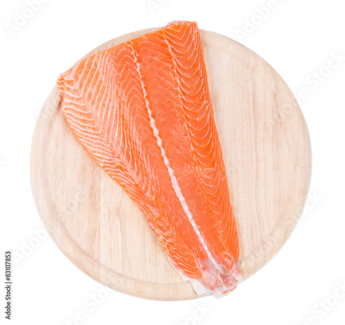 Raw salmon fillet on wood platter.