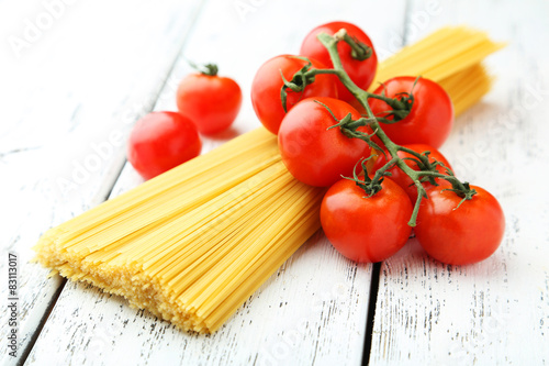 Spaghetti with tomatoes on white wooden background