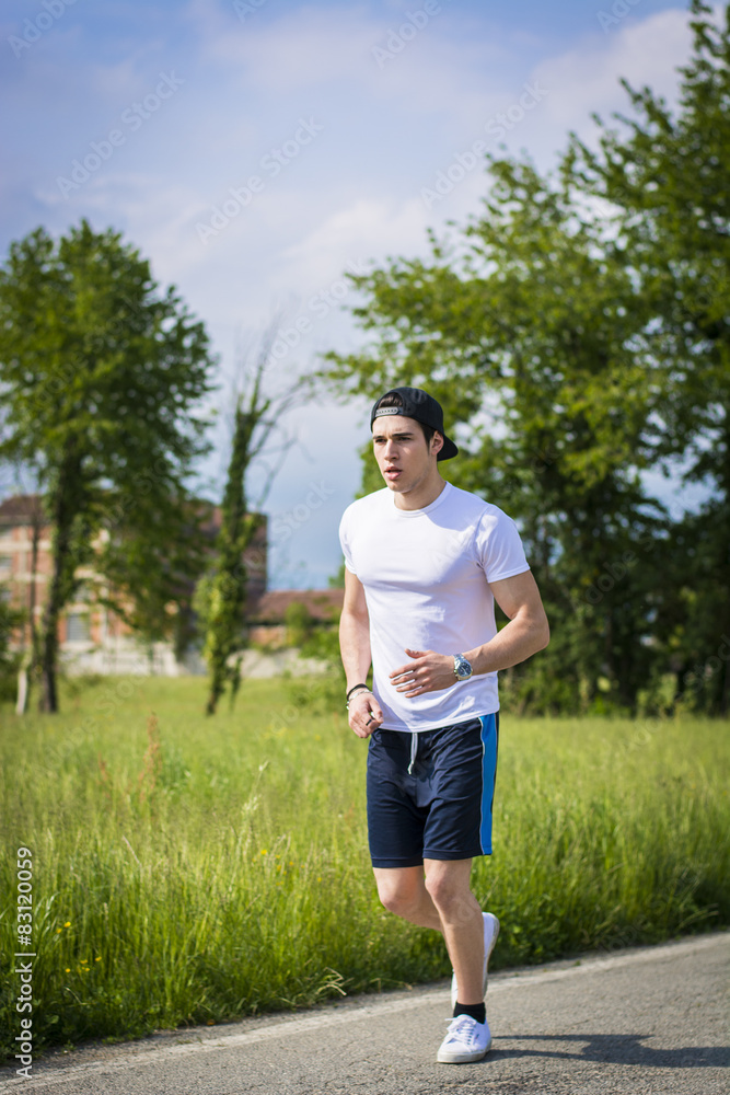 Young man running and jogging on road in country